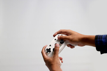 Hand holding a gamepad or joystick against a white background with empty copy space for text or...