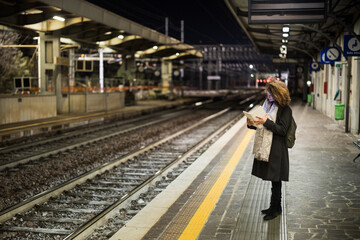Adult Woman Tourist Using Tablet at Railway Station While Waiting Alone for Train in Early Morning