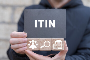 Man holding wooden cubes with icons and black sticky note with acronym: ITIN. ITIN - Individual Taxpayer Identification Number Business concept. - obrazy, fototapety, plakaty