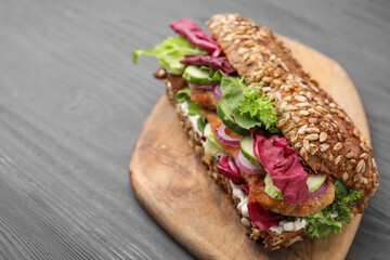 Delicious sandwich with schnitzel on dark wooden table, closeup. Space for text