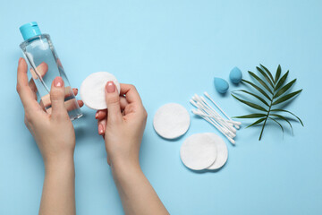 Woman with makeup remover, sponges, cotton pads and buds on light blue background, top view - obrazy, fototapety, plakaty