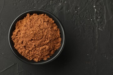 Aromatic cinnamon powder on black table, top view. Space for text
