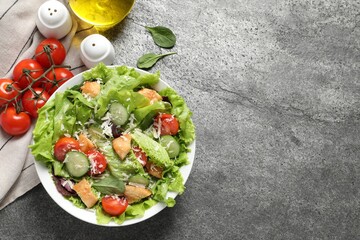 Delicious salad with chicken, cheese and vegetables served on grey table, flat lay. Space for text