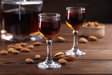 Liqueur glasses with tasty amaretto and almonds on wooden table, closeup
