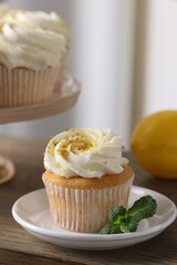 Delicious lemon cupcakes with white cream and mint on table, closeup