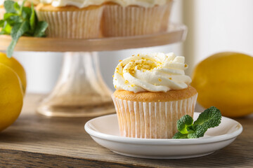 Delicious lemon cupcake with white cream and mint on wooden table, closeup