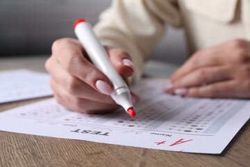 School grade. Teacher writing letter A with plus symbol on answer sheet at wooden table, closeup - obrazy, fototapety, plakaty