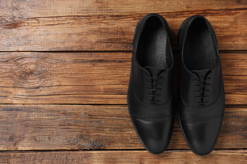 Pair of black leather men shoes on wooden background, top view. Space for text