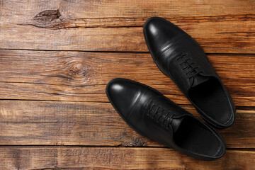 Pair of black leather men shoes on wooden background, top view. Space for text