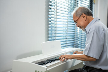 Asian attractive senior mature man play piano in living room at home. 