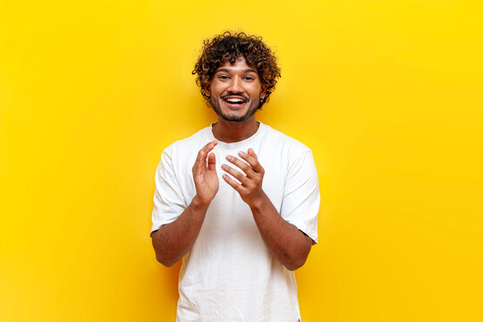 young indian guy laughing and cheering looking at the camera on a yellow isolated background