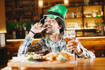 Indian guy in a green hat drinks beer