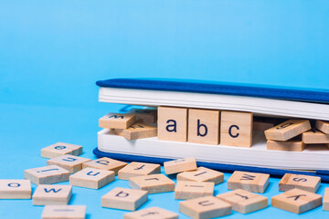 English alphabet made of square wooden tiles with the English alphabet scattered on blue...