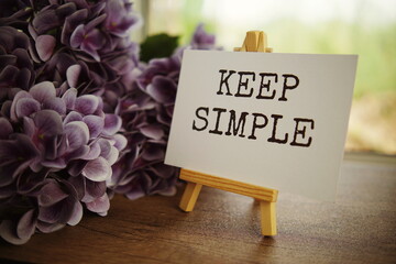 Keep simple text message text message on paper card with wooden easel on wooden table background,...