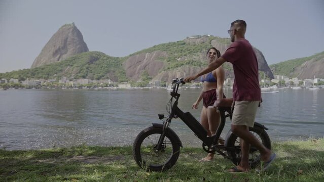 Jovem casal caminhando pela costa, conversando, empurrando uma bicicleta. Cinematico 4k.