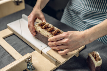 Cutting of homemade natural chocolate soap on a professional wood cutter. A means of eco-friendly hygiene and pleasant gifts