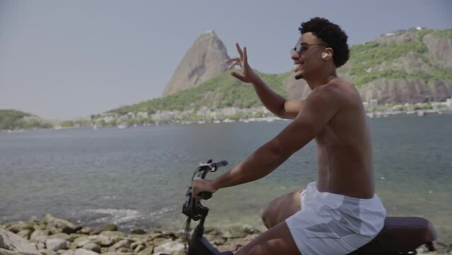 Homem jovem, sem camisa, andando de bicicleta a beira mar. Cinematico 4k.
