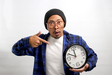 An excited young Asian man, dressed in a beanie hat and casual shirt, appears pleasantly surprised...