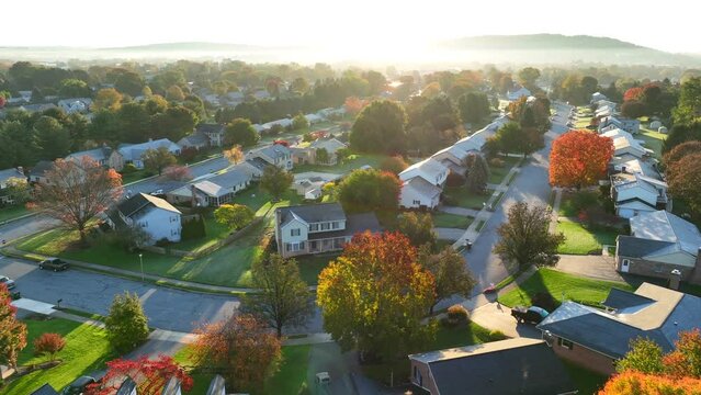 Bright sunrise over American neighborhood during autumn morning. Aerial shot of houses and homes in suburb.
