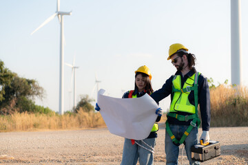 Engineer and worker discussing on a wind turbine farm with blueprints