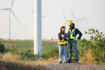 Engineer and worker discussing on a wind turbine farm with blueprints