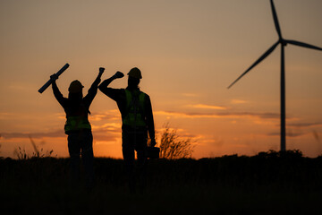 Silhouette of Engineer in charge of wind energy against a background of wind turbines.