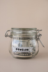 Saving Money In Glass Jar filled with Dollars banknotes. PENSION transcription in front of jar....