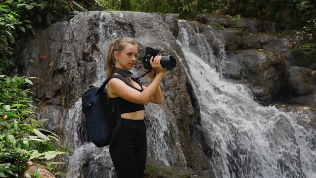 Woman photographer taking pictures of waterfall. Adventure and travel photography.