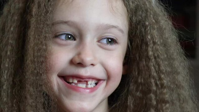 Cute little girl smiles and shows her fallen front milk teeth. Teeth growth. Close-up. Portrait of a 6-year-old rebec