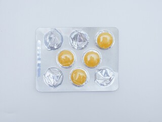 Yellow pills in blister pack isolated on white background, top view.