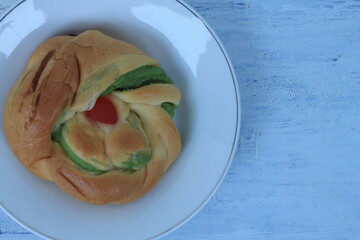 Round shape torn bread with green jam in plate on table