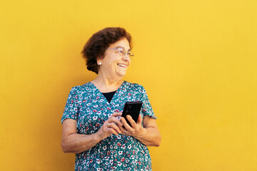 Smiling old woman using smartphone outdoors