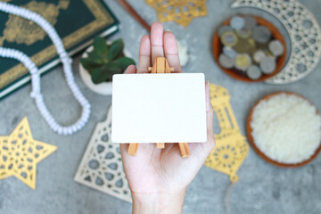 Portrait of muslim hands holding a white blank paper for mockup with Islamic decoration on the background, top view