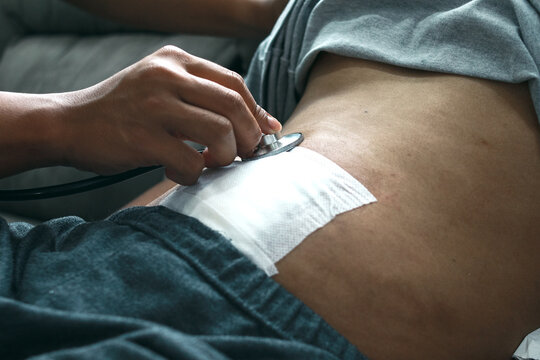 Doctor's hand using stethoscope checking patient stomach in the clinic, post appendectomy surgery