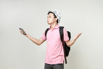 Asian man backpacker hold mobile phone with confused expression. travelling concept. on isolated...