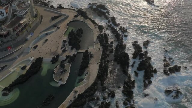 volcanic pools of Porto Moniz in Madeira Potrugal fottage with drone of cliffs, ocean, atural bathing spots, houses filmed at sunset.
