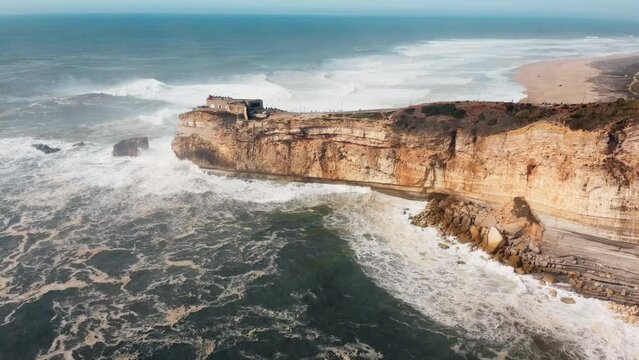 Aerial view of rocky oecan with crashing waves in Nazare, Portugal