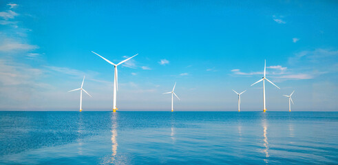 Windmill turbines generating electric green energy with a blue sky green energy concept in the...