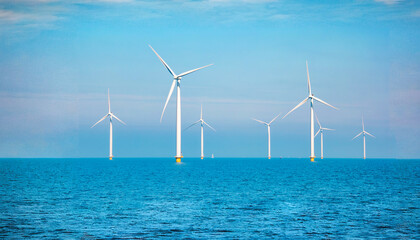 Windmill turbines generating electric green energy with a blue sky green energy concept in the...