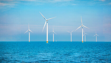 Windmill turbines generating electric green energy with a blue sky green energy concept in the Netherlands, windmill turbines at sea