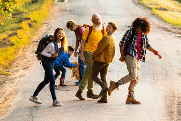 Naklejka premium This vibrant photograph captures a diverse group of individuals sharing a joyful moment on a country road. The composition shows them engaged in lively interaction, with laughter and smiles all around