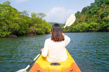 back view of woman kayaking In the green forest she does water sport activities.