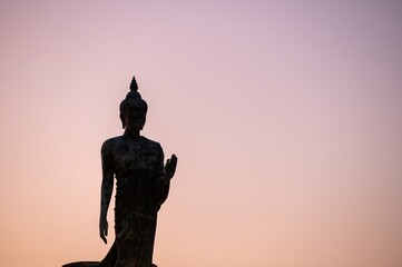 Stand big Buddha Statue in silhouette sun set Light background in park of Thailand temple.Yellow...