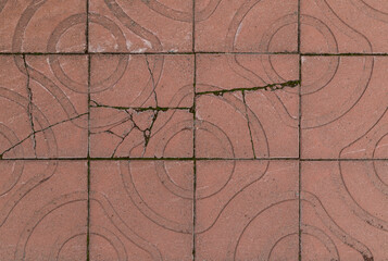 Broken and weathered red square paving stones or blocks with geometric shapes outdoors, viewed from above. High resolution full frame textured background.