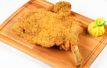 Viennese schnitzel. Close up photo of a big beef viennese schnitzel on a wooden plate ready to be...