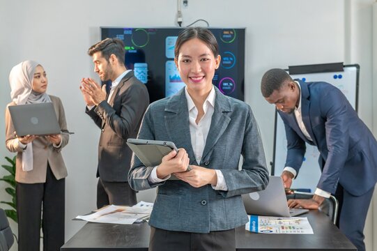 officer leader supervisor and manager woman smile and carry hold notebook tablet in office company. leader senior manager looking and carry laptop in meeting room multiracial teamwork background.