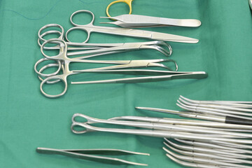 Surgical clamps and medical equipment on green surgical tray inside operating room.Sterile surgical instrument tool equipment for surgery.Medical tool - obrazy, fototapety, plakaty