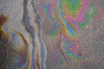 Oily film of rainbow oil or gasoline spill on the surface of a puddle, top view. Environmental problems concept