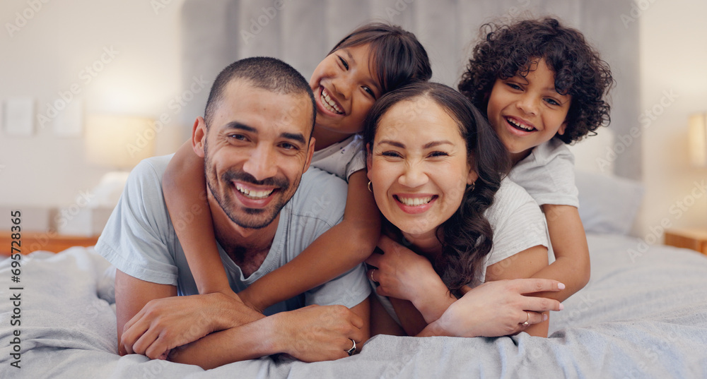 Wall mural Portrait, happy and kids with parents in bed relaxing and bonding together at family home. Smile, fun and young mother and father laying and resting with children in bedroom of modern house.