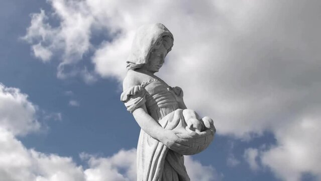 Animation of gray sculpture of woman over blue sky and clouds